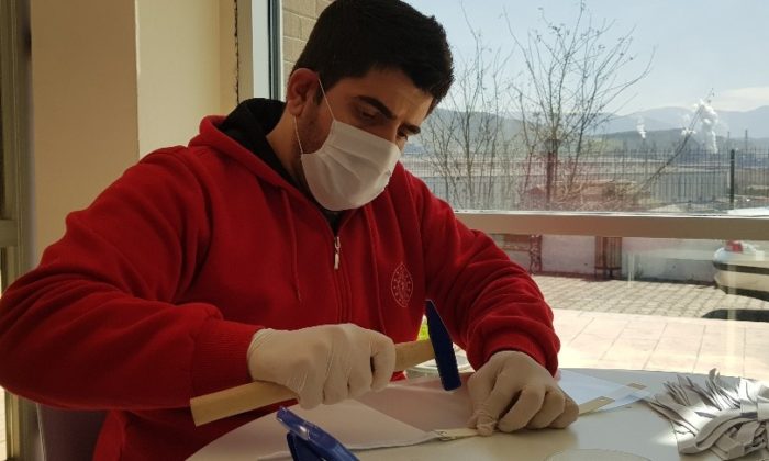 Ellerinde çekiç, delgeç ve perçinle siperlikli maske üretiyorlar